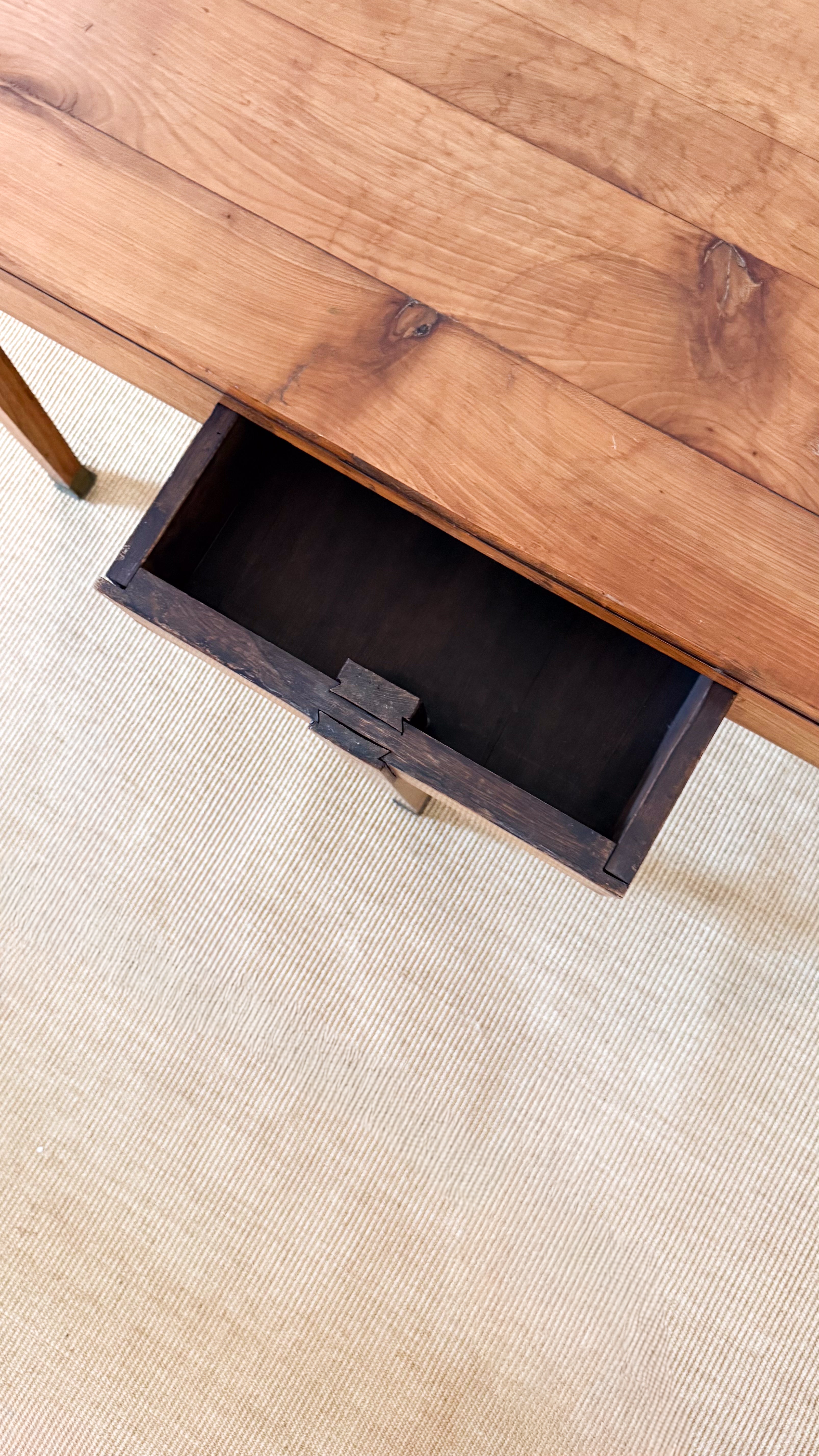 Wooden drawer being pulled out from a wooden table on a beige carpet.