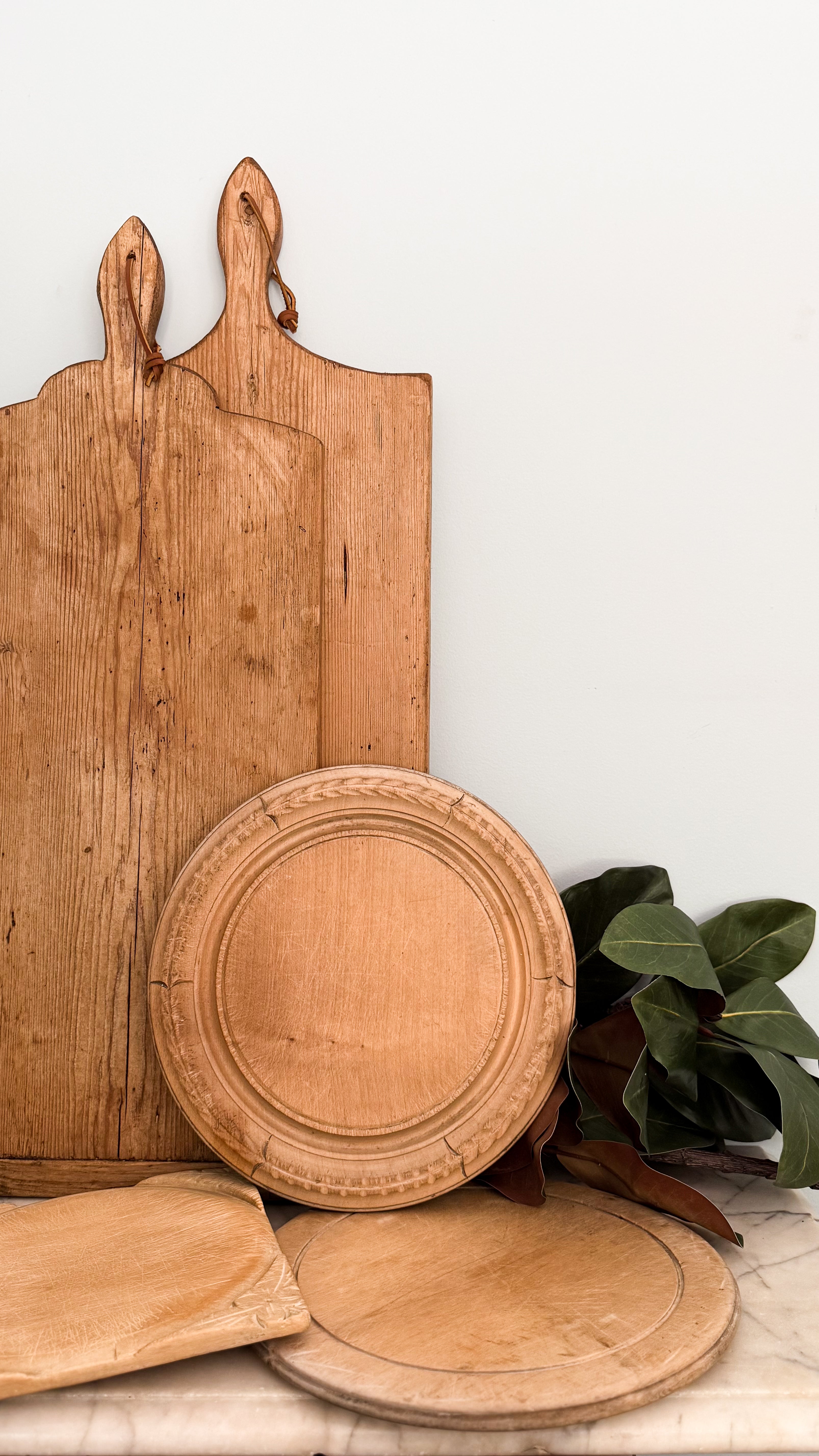 Collection of Vintage Bread Boards on a marble counter alongside Faux Magnolia Branches