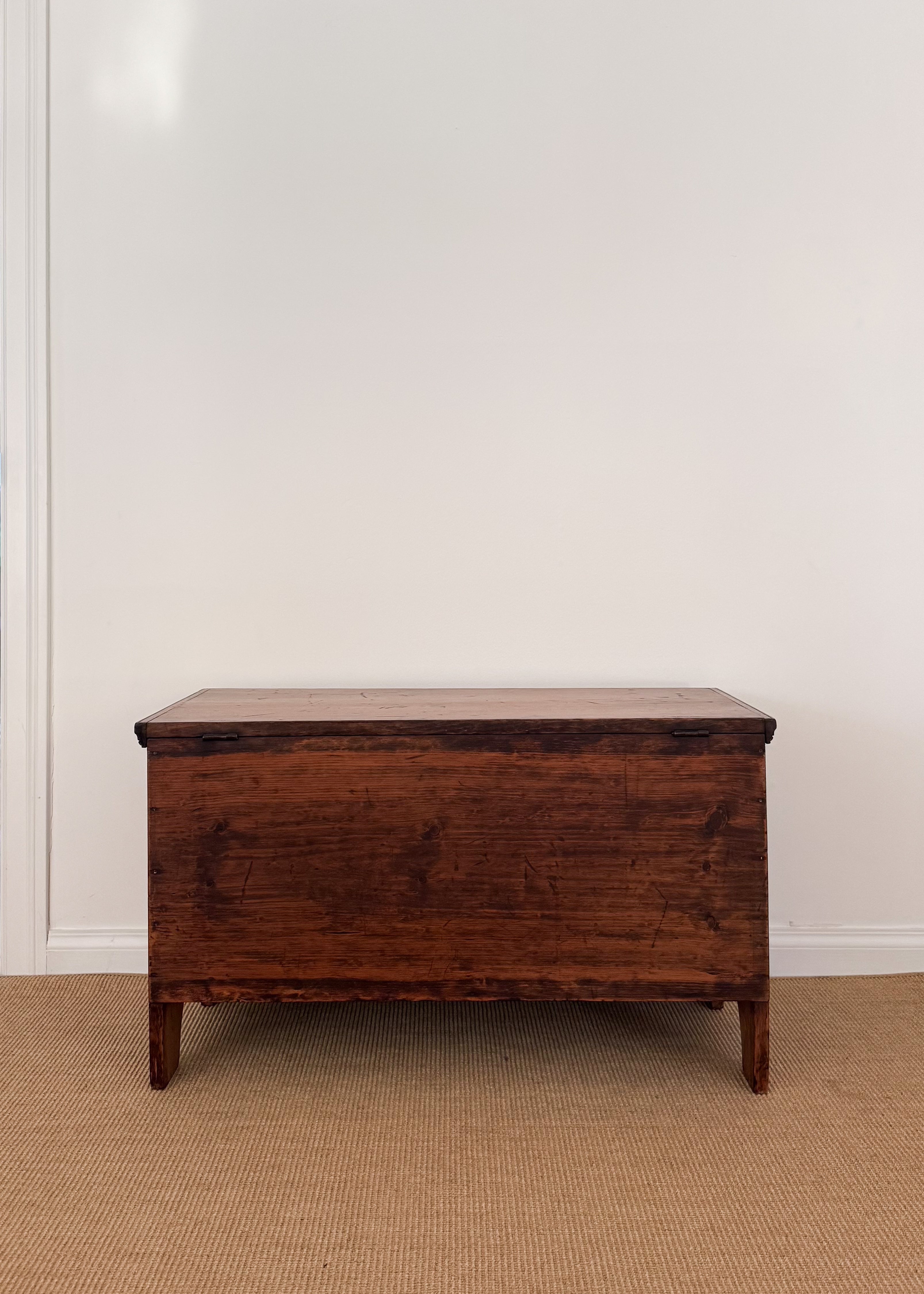 Wooden chest on a beige carpet with a white wall background