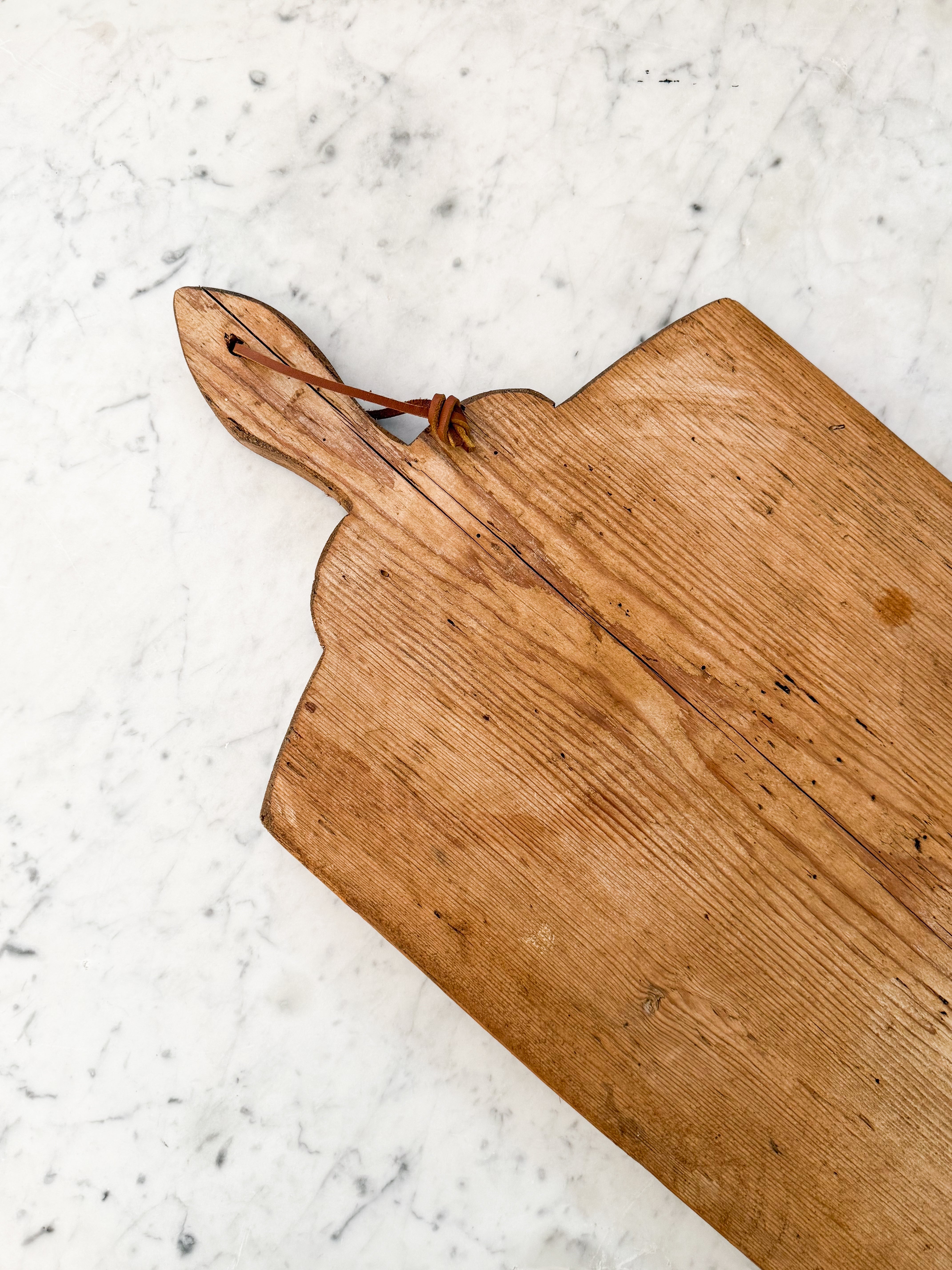 Handle of Vintage European Bread Board on a marble counter.