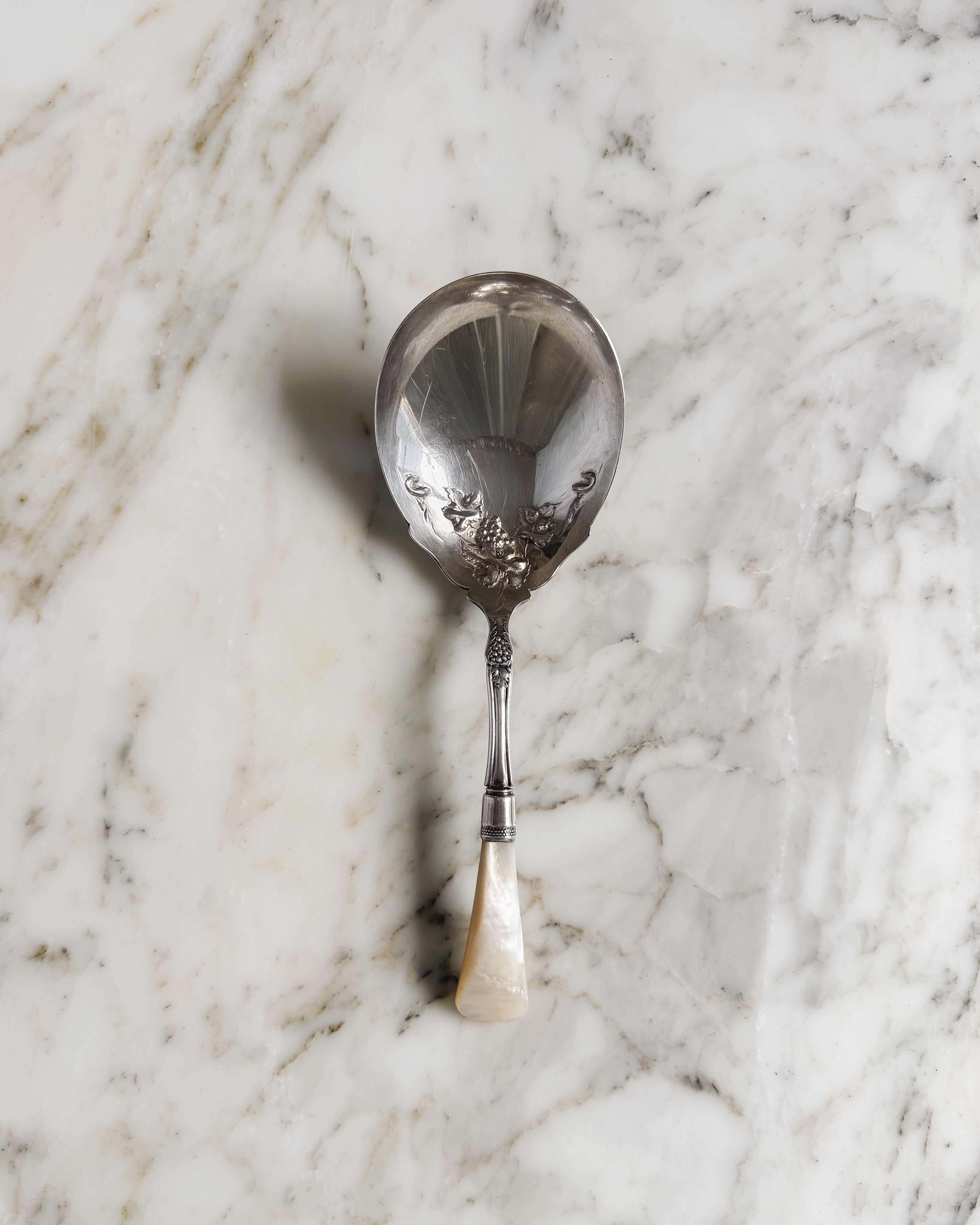 Antique Edwardian sterling silver serving spoon with mother-of-pearl handle and grape motif.