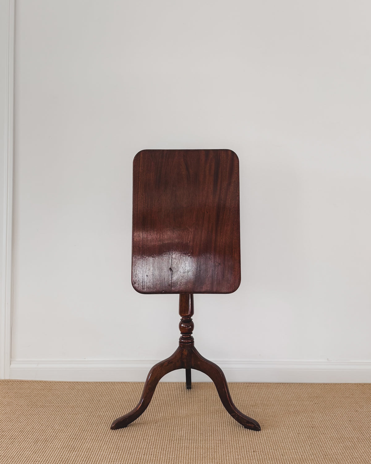 Antique Sheraton mahogany table with rectangular top tilted upright above the tripod base