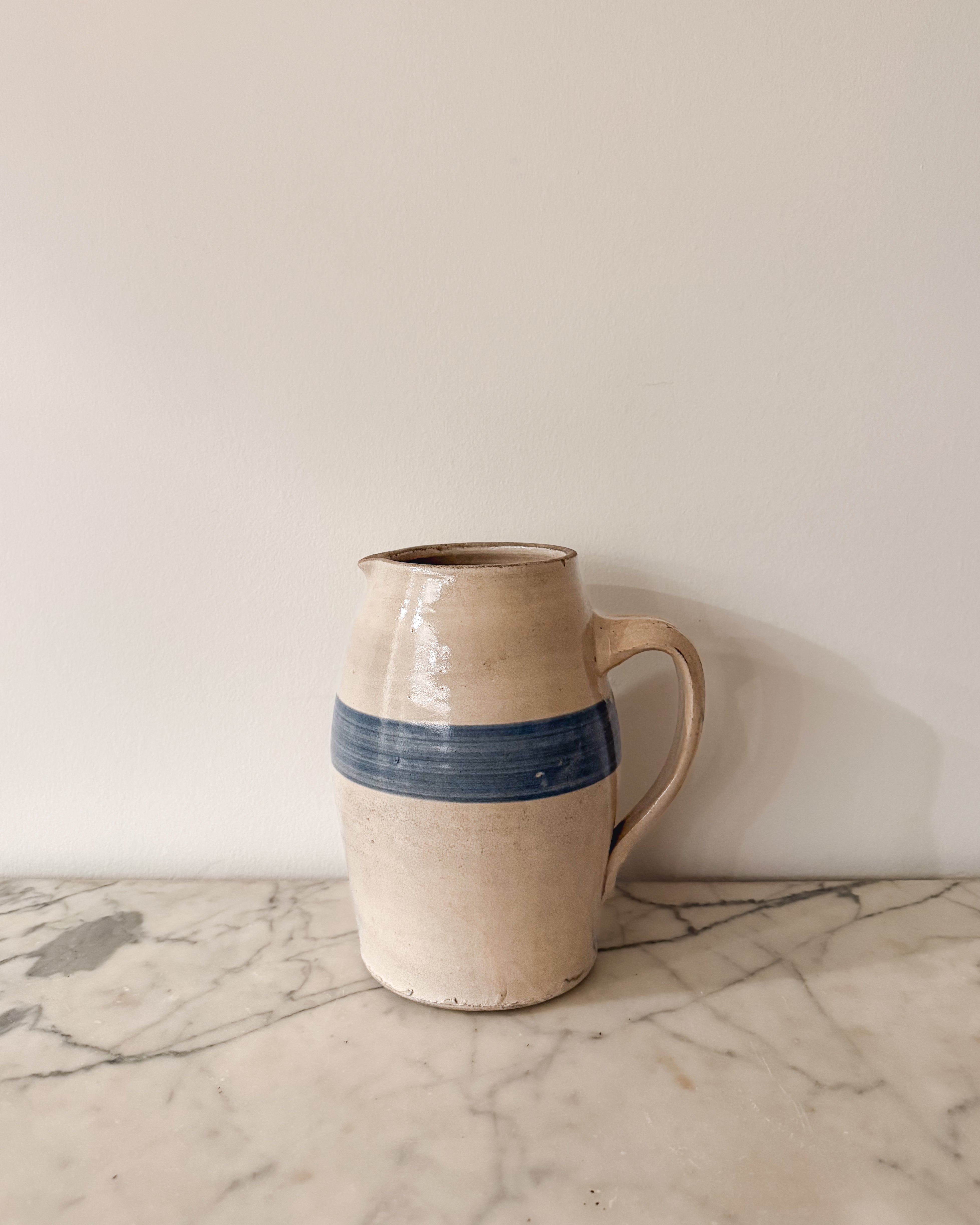 Early 20th century antique stoneware pitcher with cobalt blue band and cream glaze.