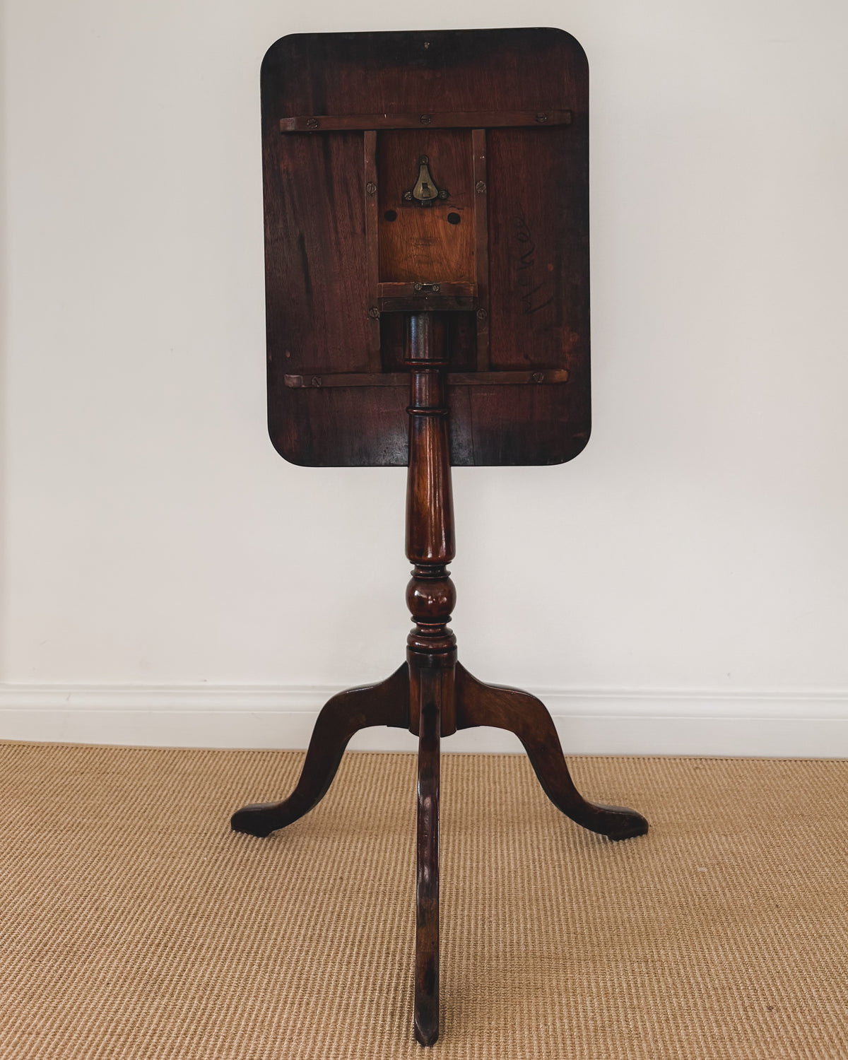 Underside of antique mahogany tilt-top table showing the traditional tilting mechanism and support structure
