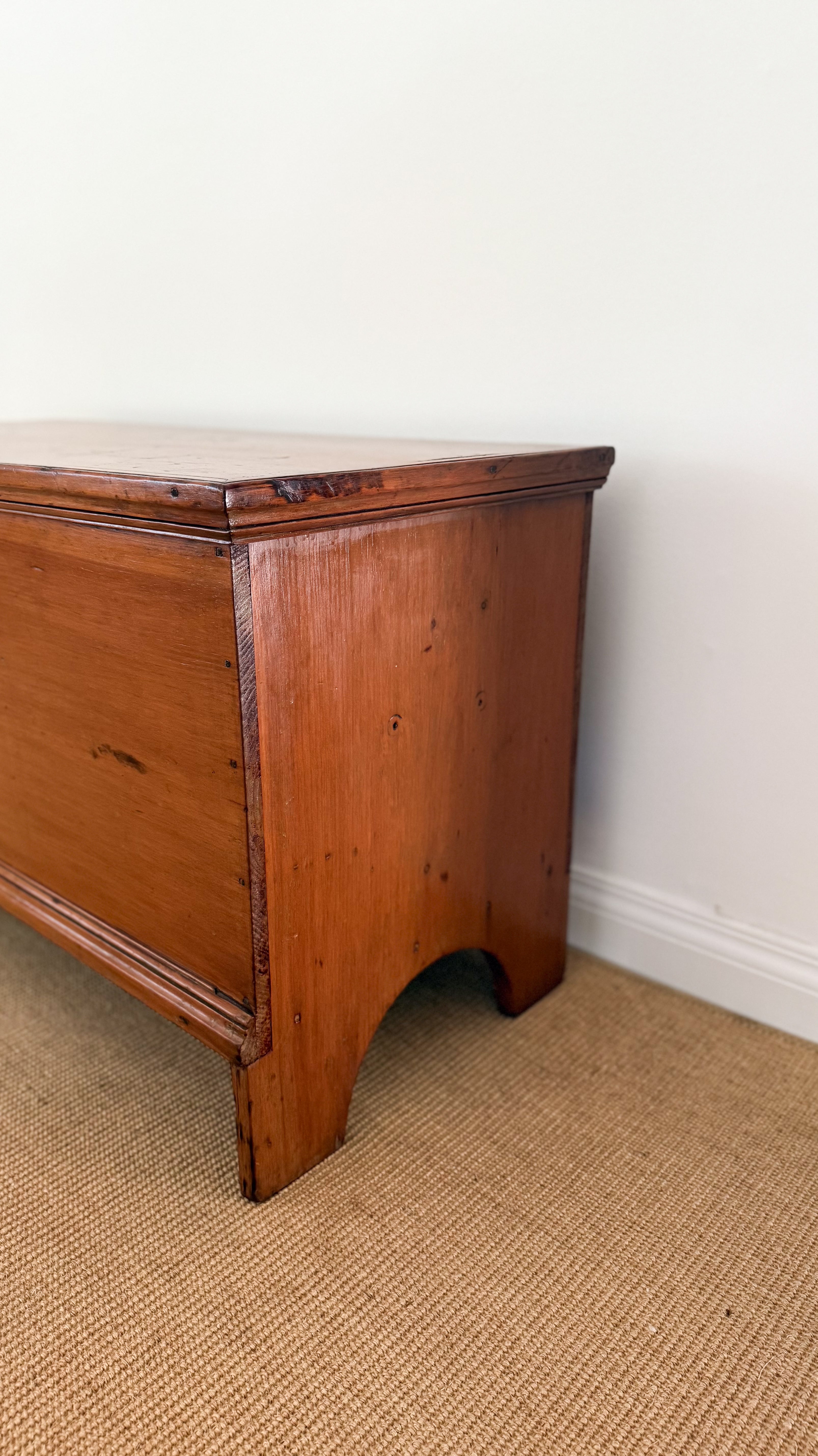 Antique wooden dresser against a white wall on a beige carpet