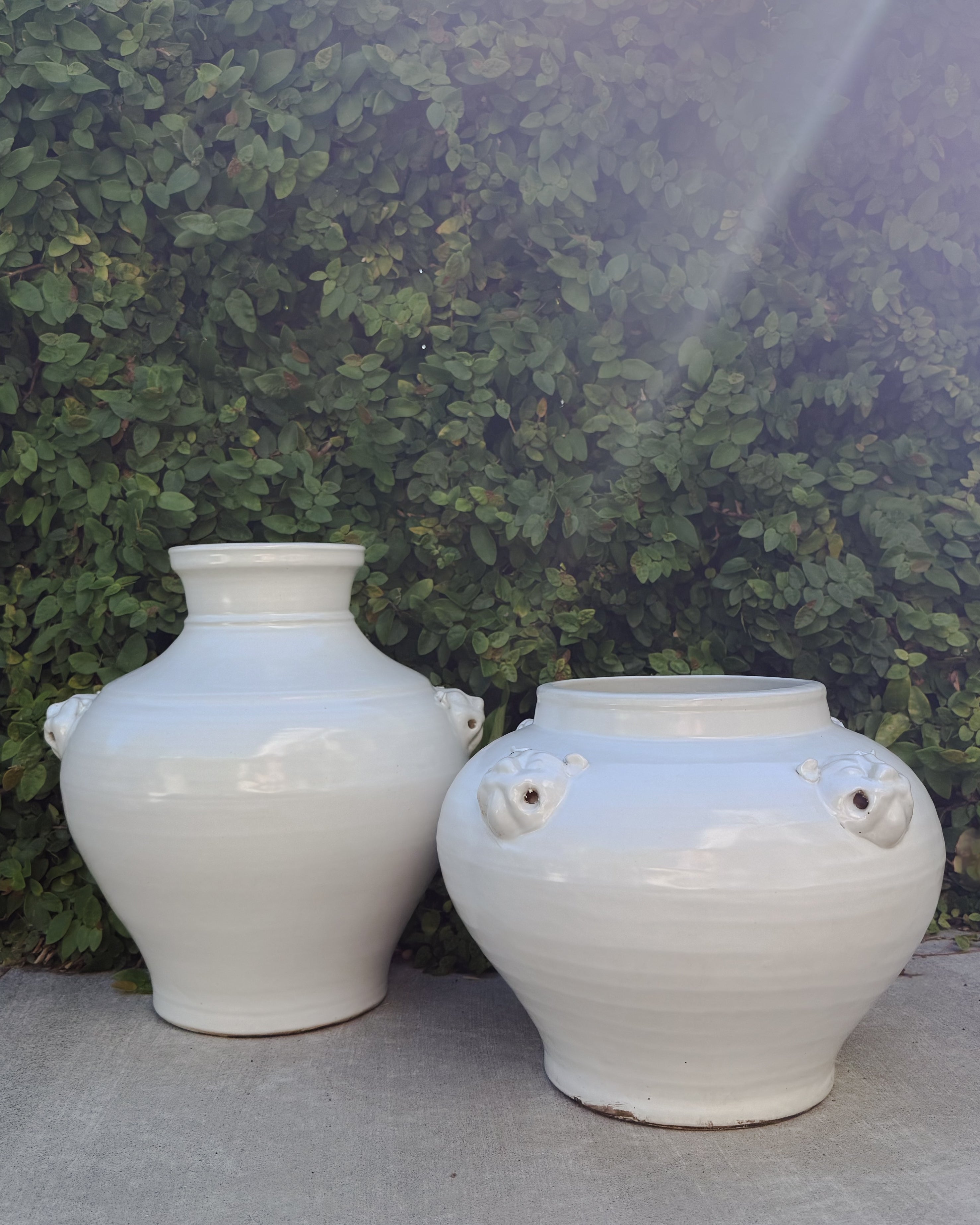 Two McConnell handmade ceramic estate vessels with lion head accents. There is a taller more narrow form and a wider, lower, round form.