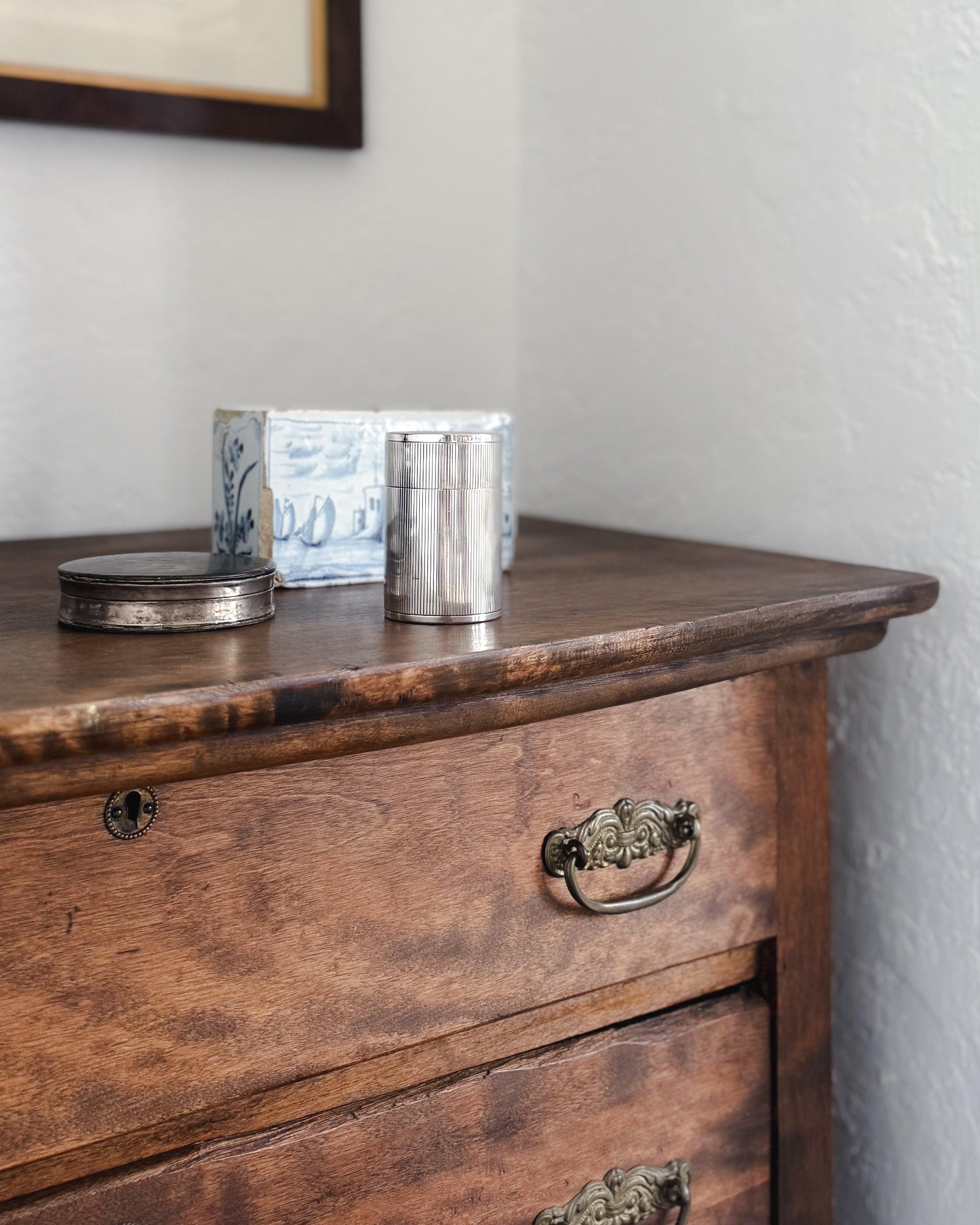 Vintage European silver-plated canister with finely fluted detailing styled on an antique dresser beside vintage silver and blue-and-white delft pottery.