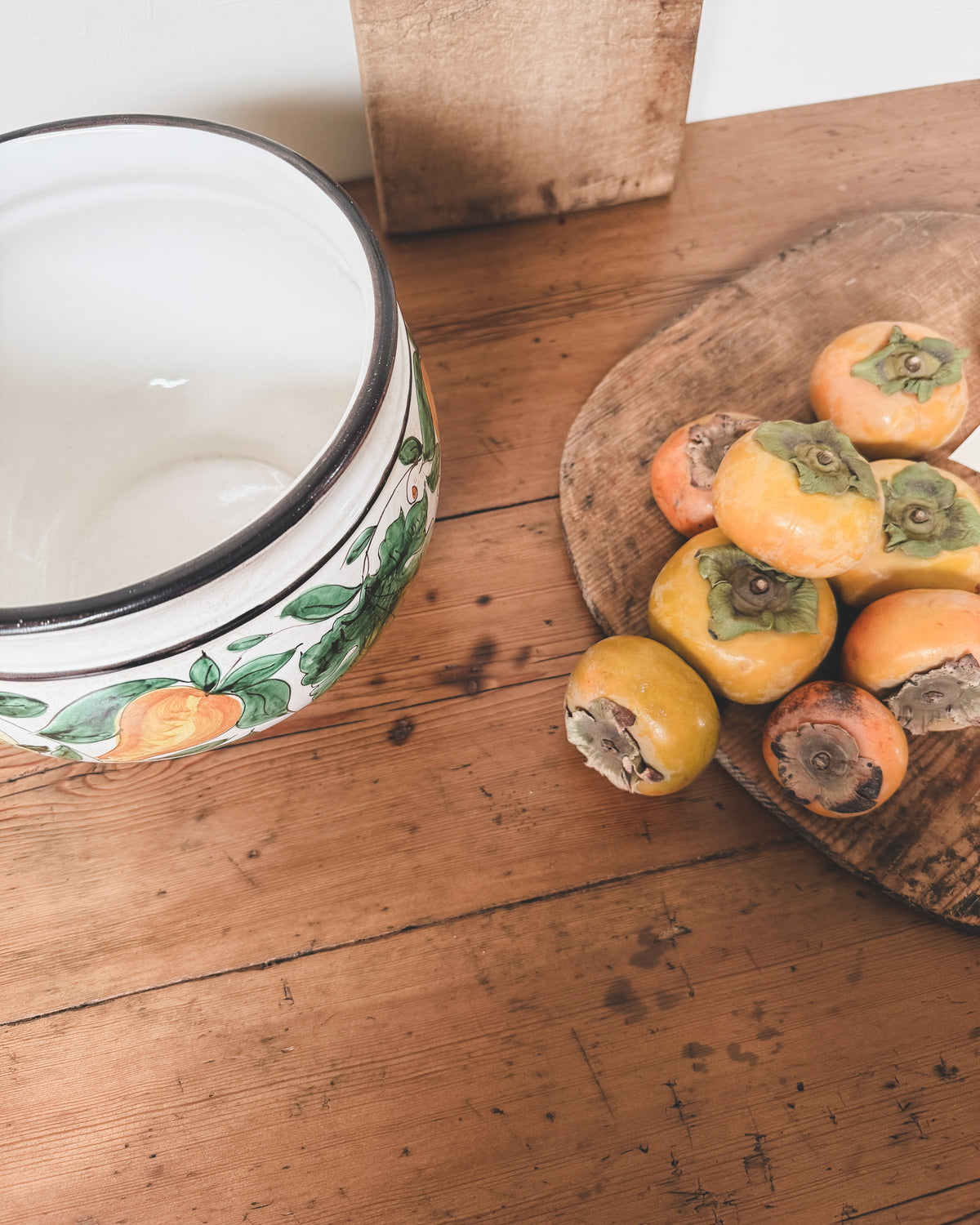 vintage italian planter on an antique farmhouse pine table with vintage european bread boards and persimmons.