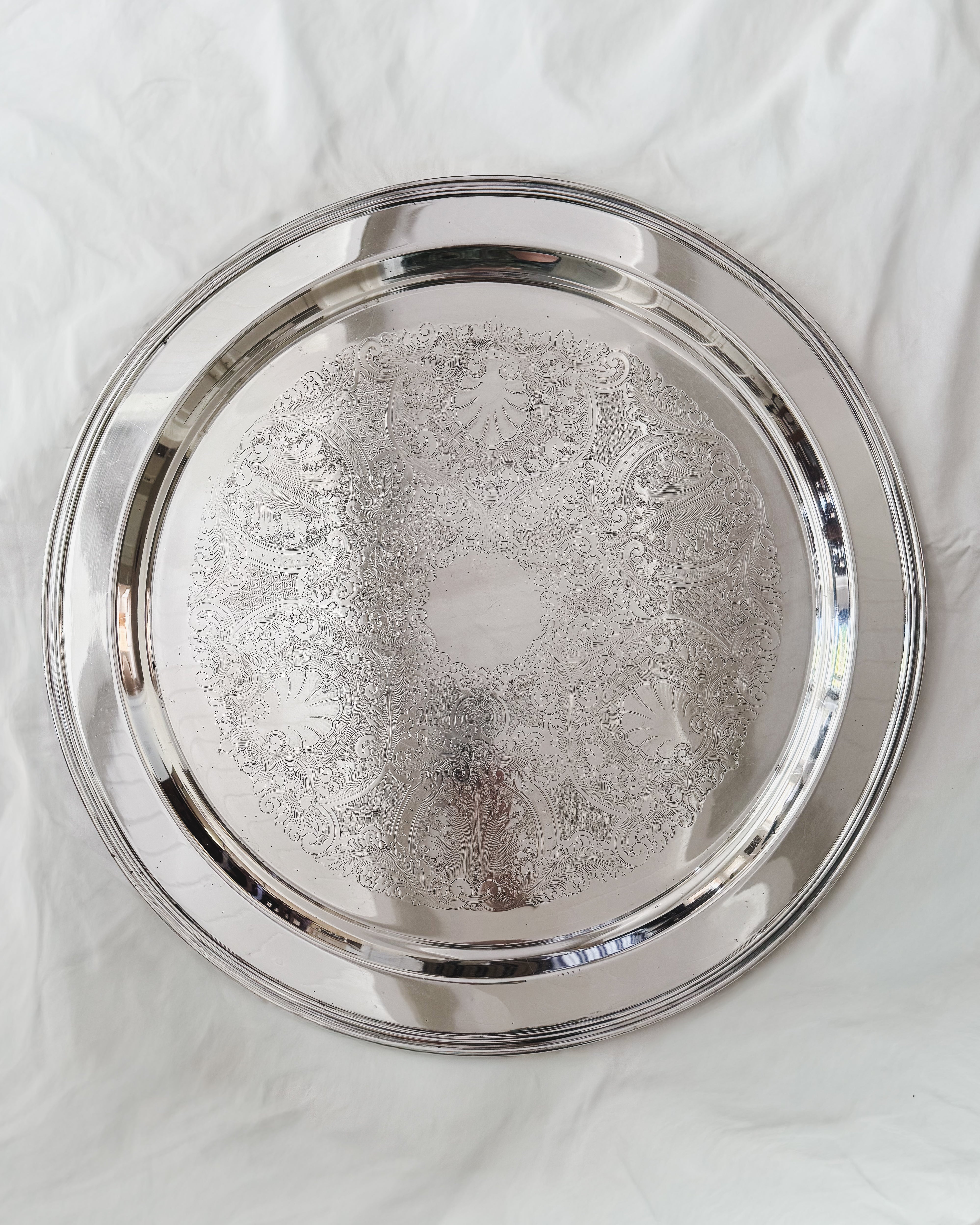 Vintage silver plate oversized round serving tray with engraved shell and foliate decoration, 21 inches