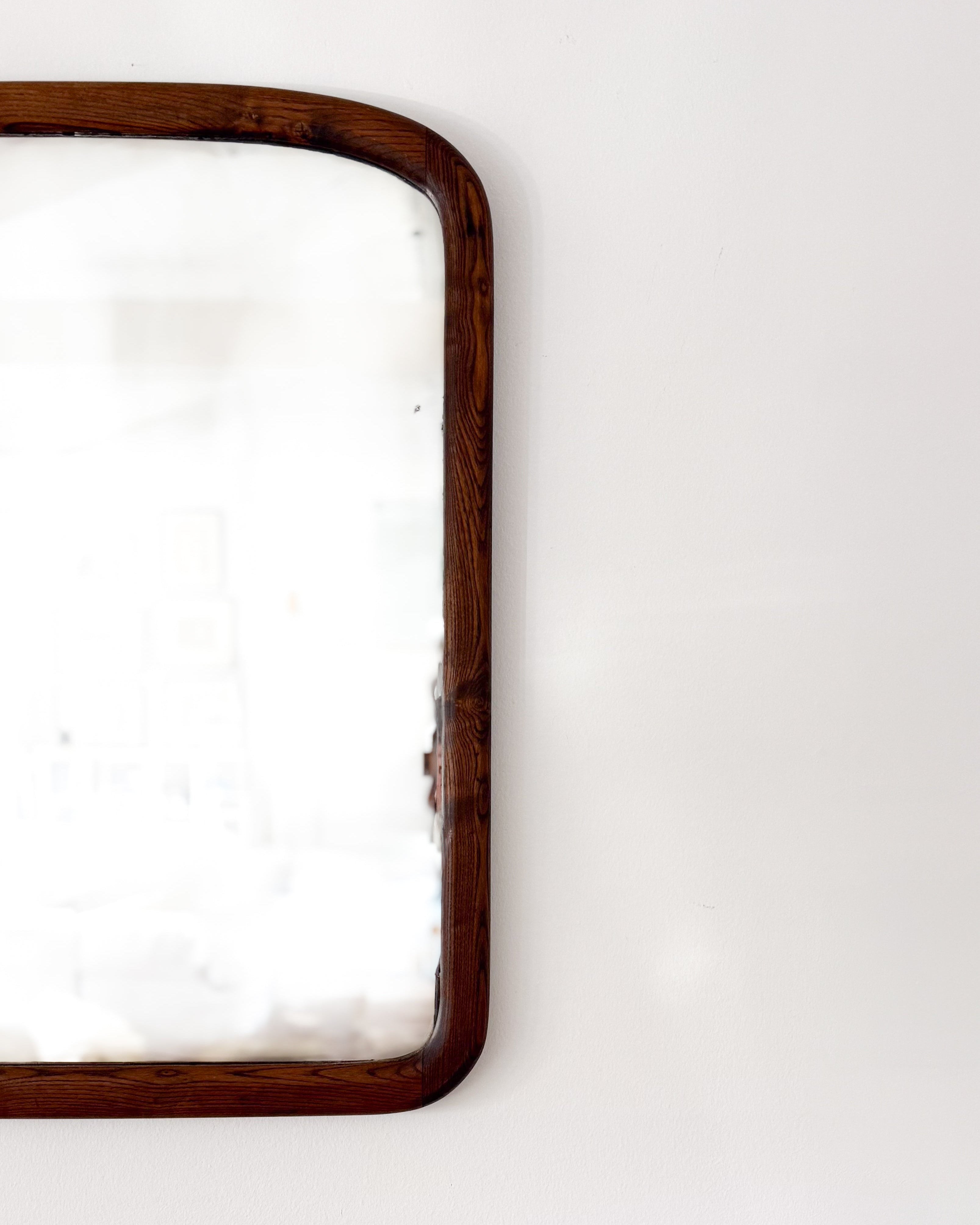 Detail of the richly grained oak frame and rounded corner of an antique 19th century American mirror