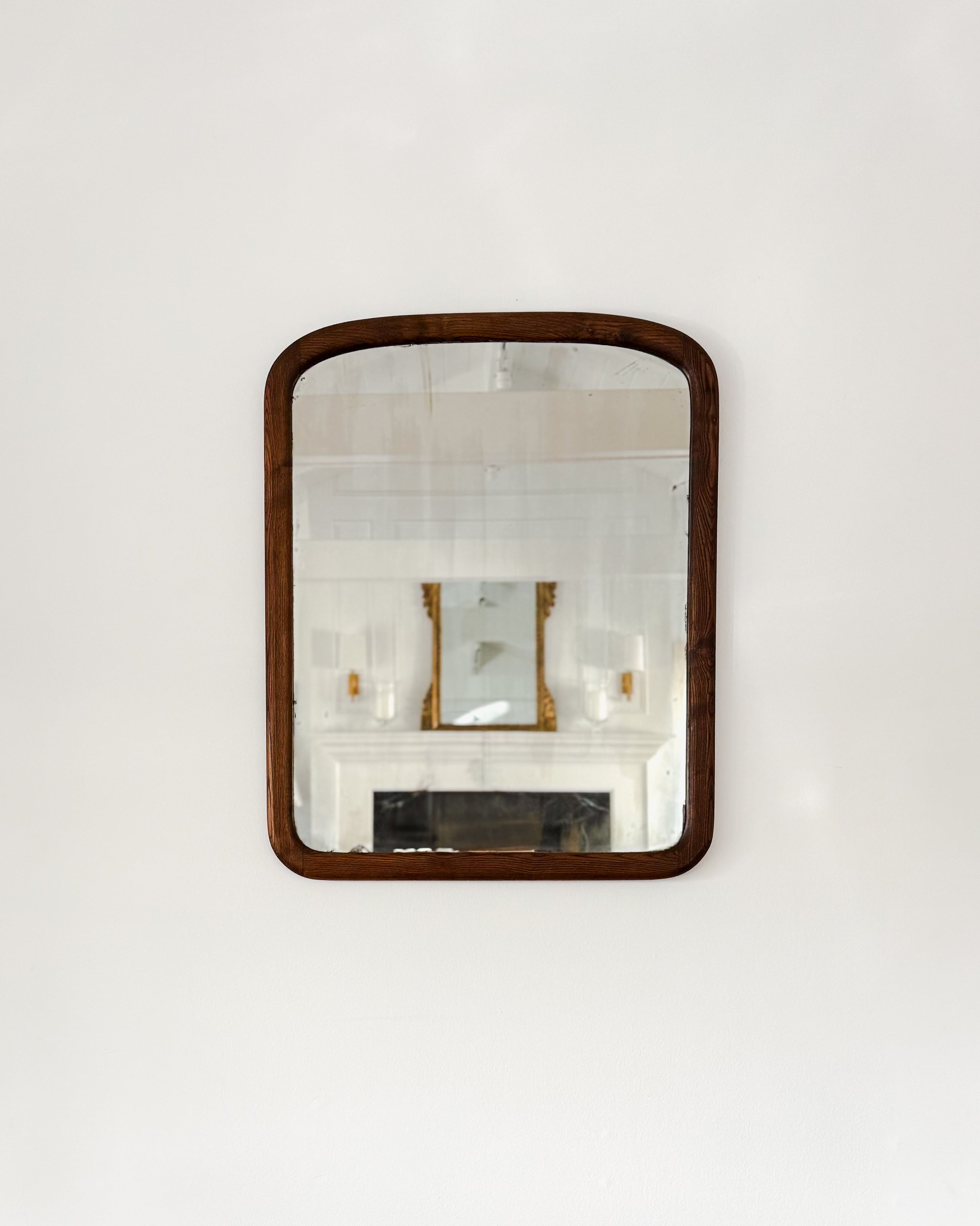 19th century antique American rectangular oak mirror with original glass and softly rounded corners hanging on a white wall.