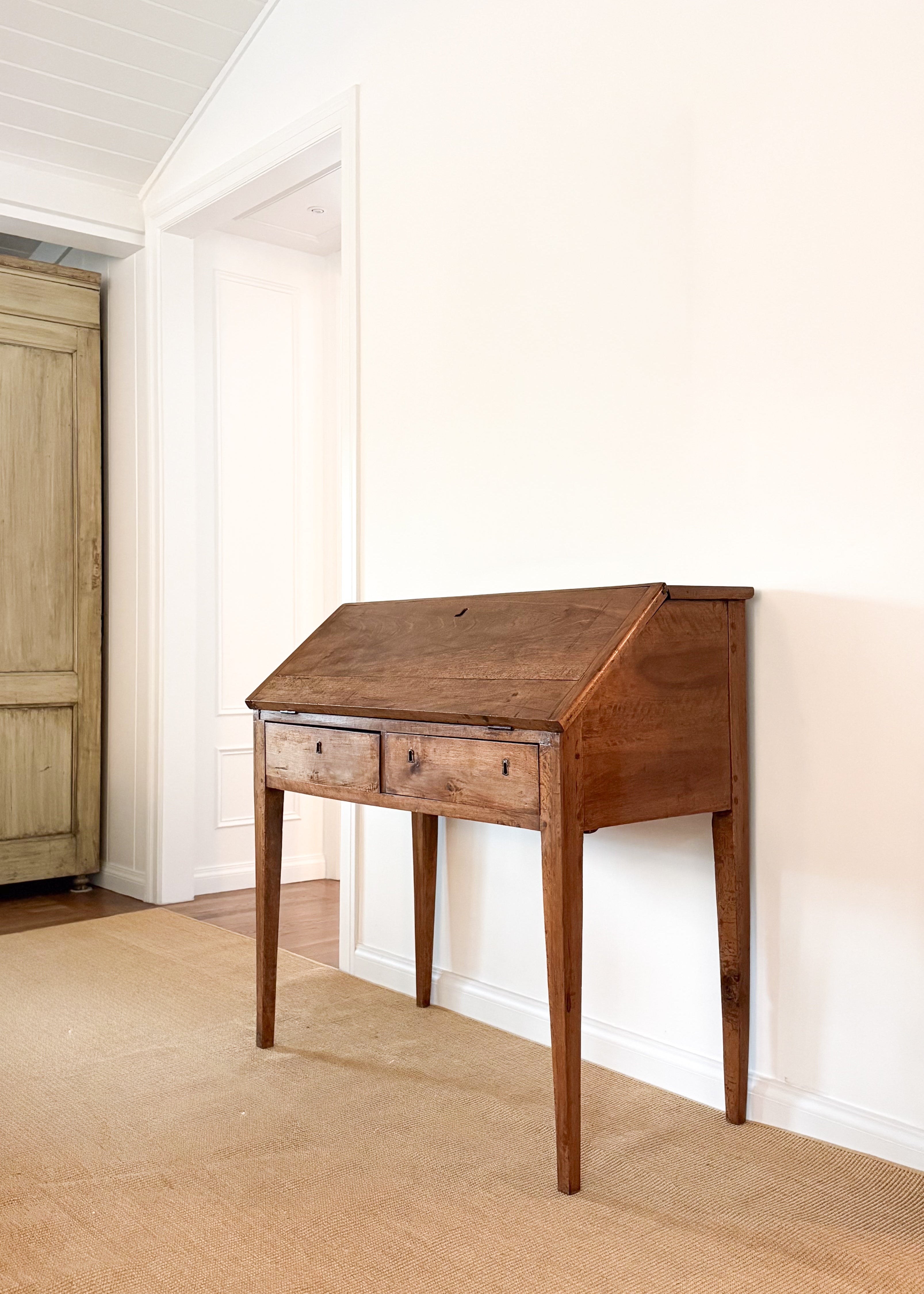Antique wood desk in a room with white walls and a wooden floor.