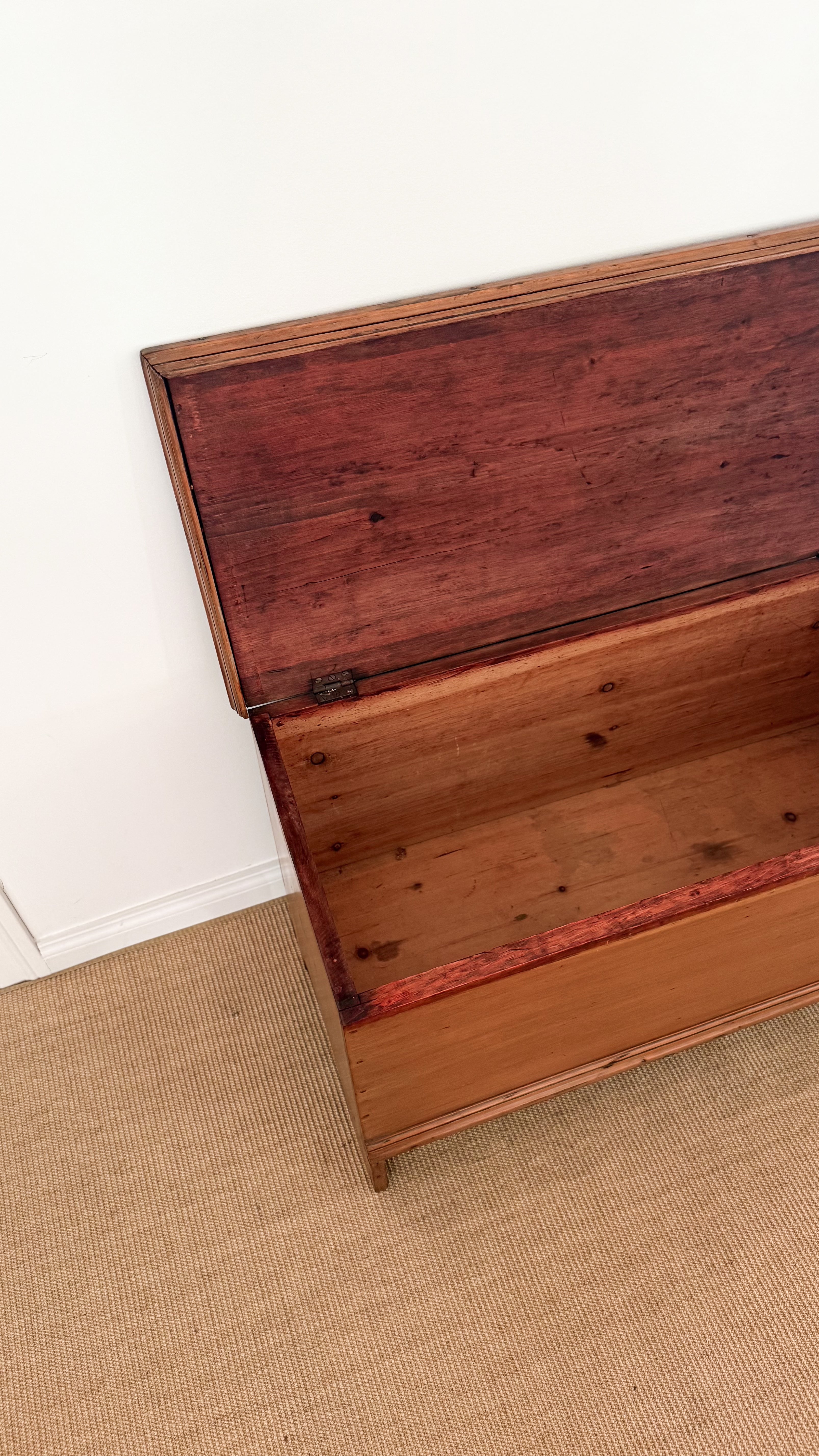Antique wooden dresser with a slanted top on a beige carpet