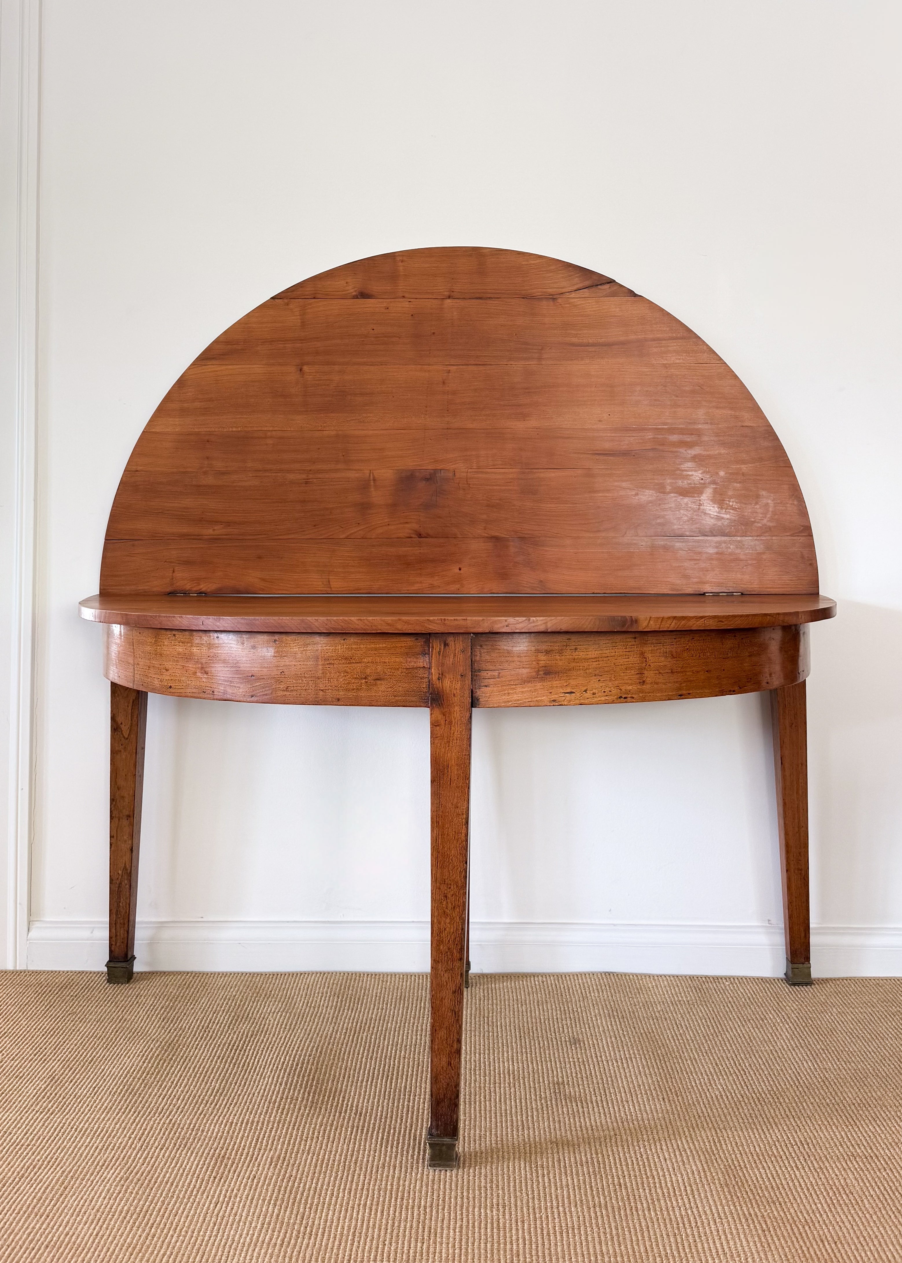 Antique folding wooden oval table against a white wall