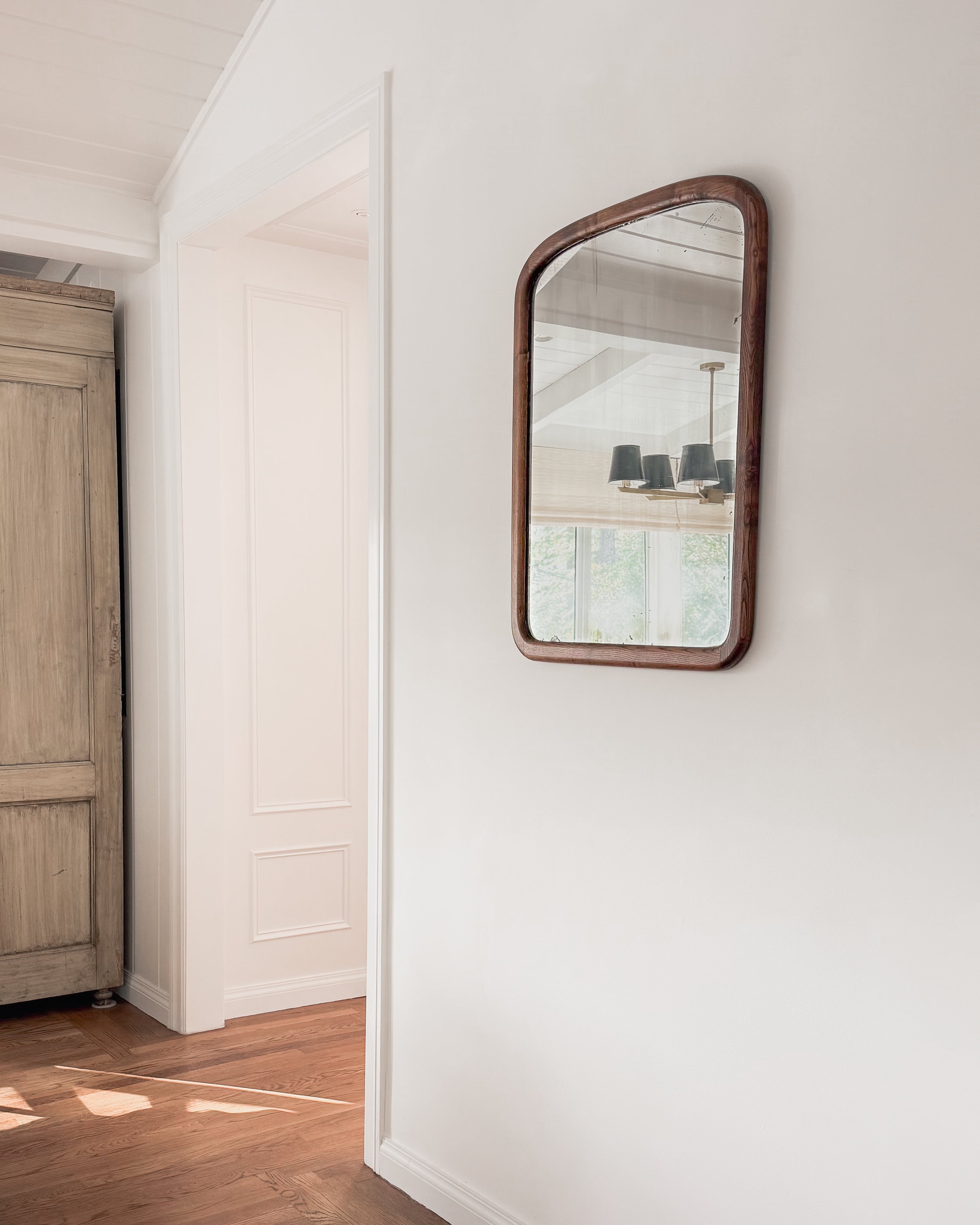 Antique 19th century American oak mirror hanging on a white wall in a home interior.