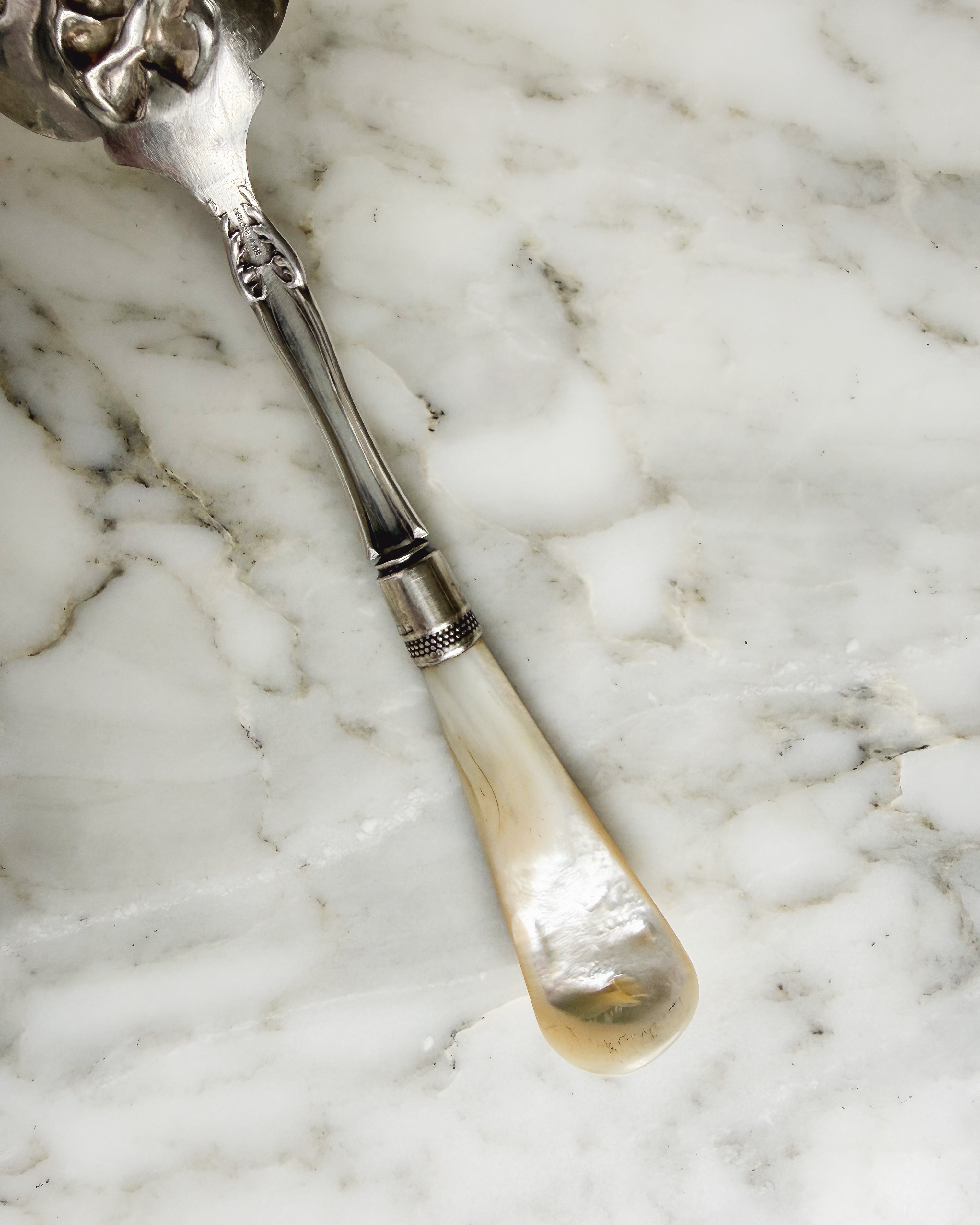 Natural mother-of-pearl handle and sterling silver collar on antique Edwardian serving spoon.