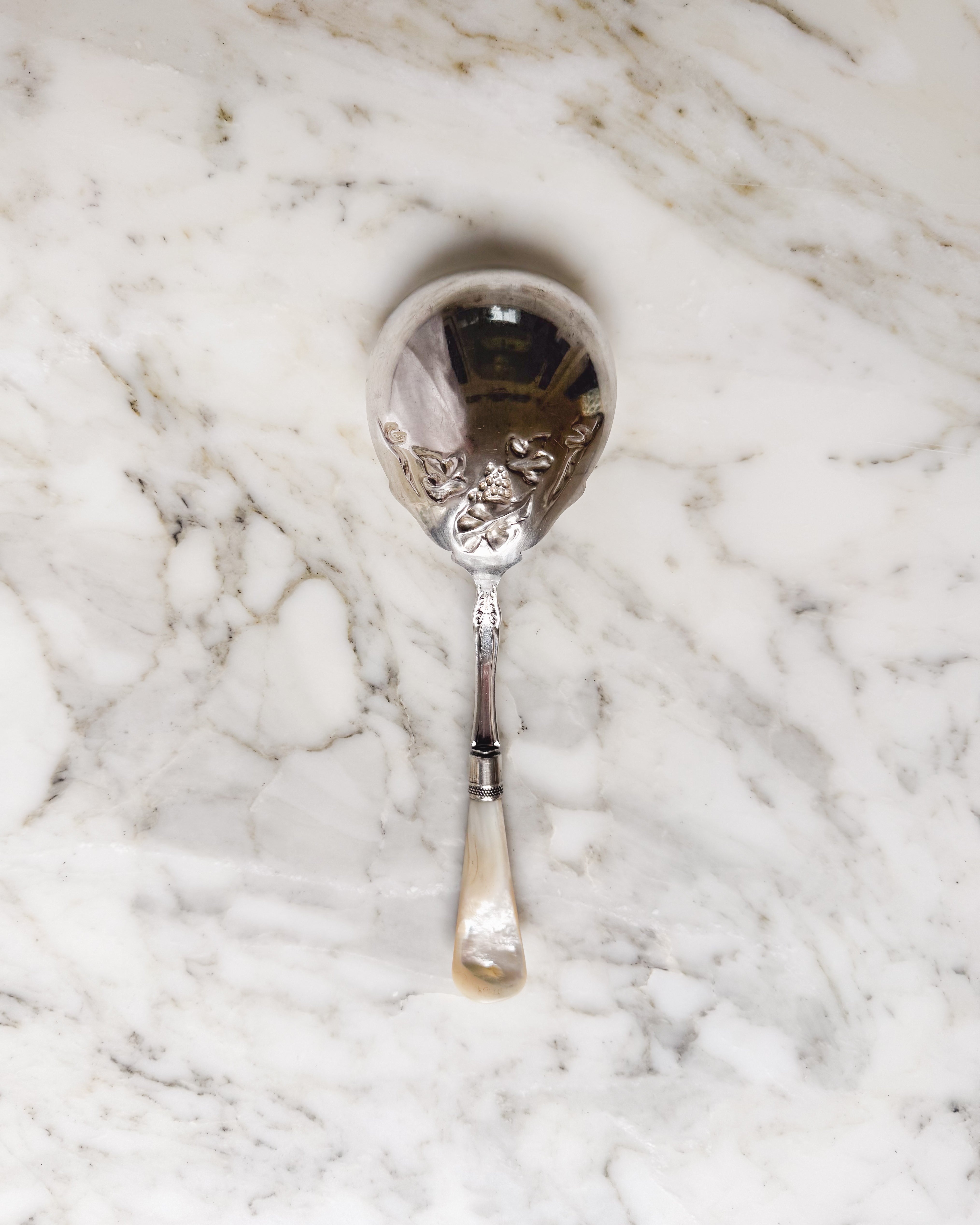 Back of antique Edwardian sterling silver serving spoon with grape motif and mother-of-pearl handle.