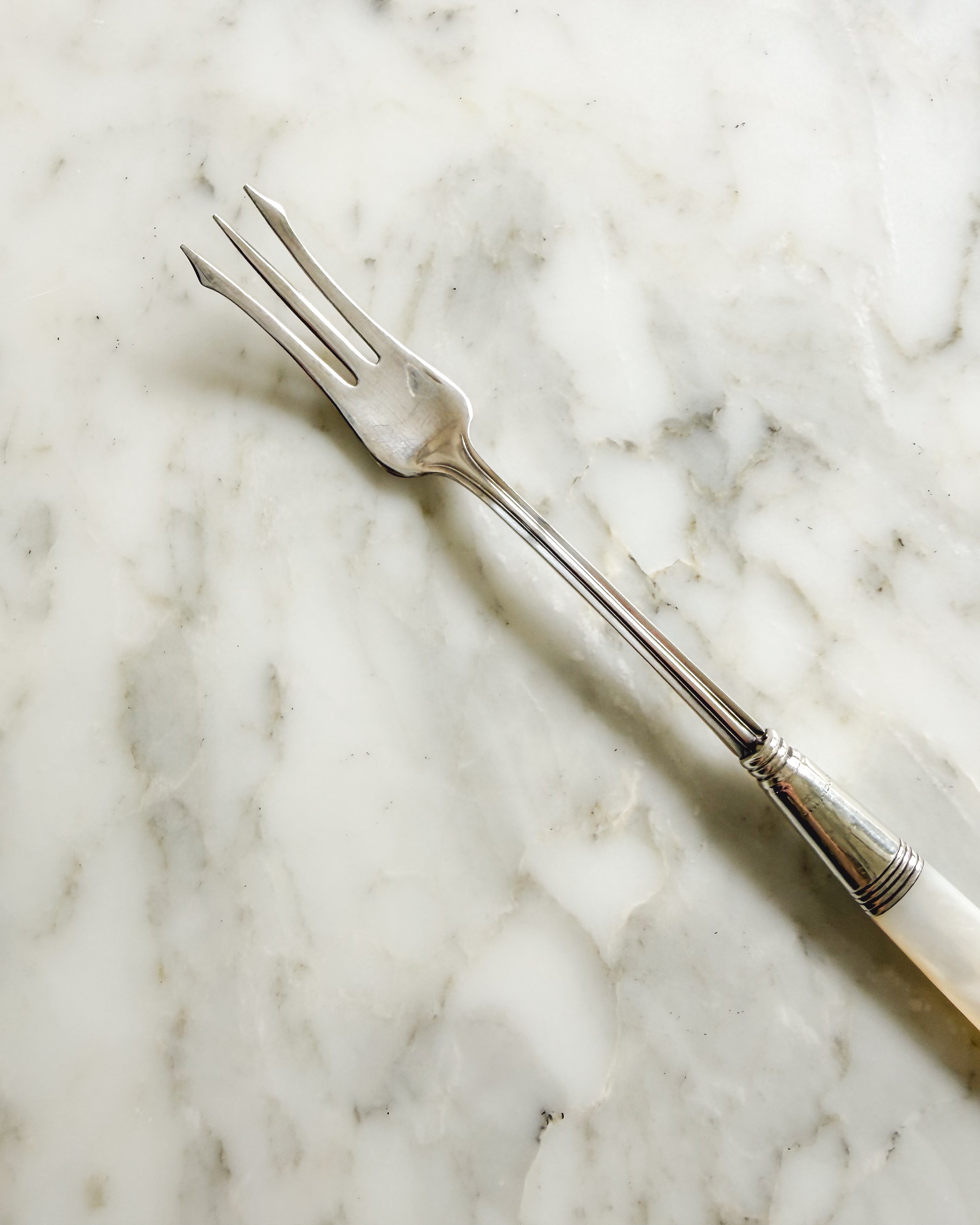 Three tine silver plated antique pickle fork  and stem with sterling silver collar and mother of pearl handle.