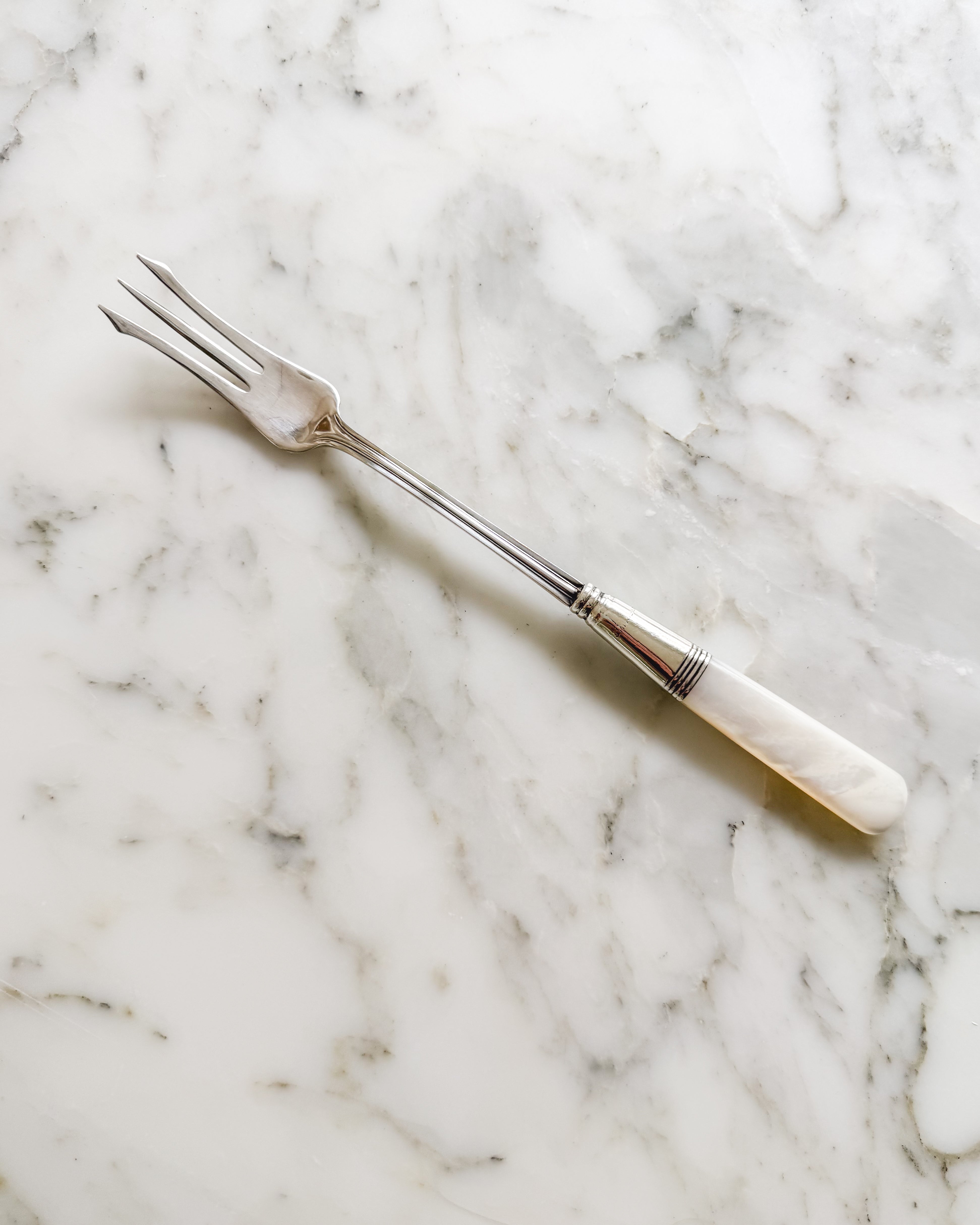 Antique sterling silver pickle fork with mother-of-pearl handle.