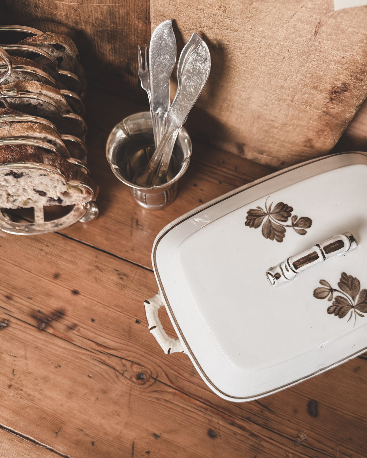 Vintage silver petite cup holding flatware on an antique wood tabletop