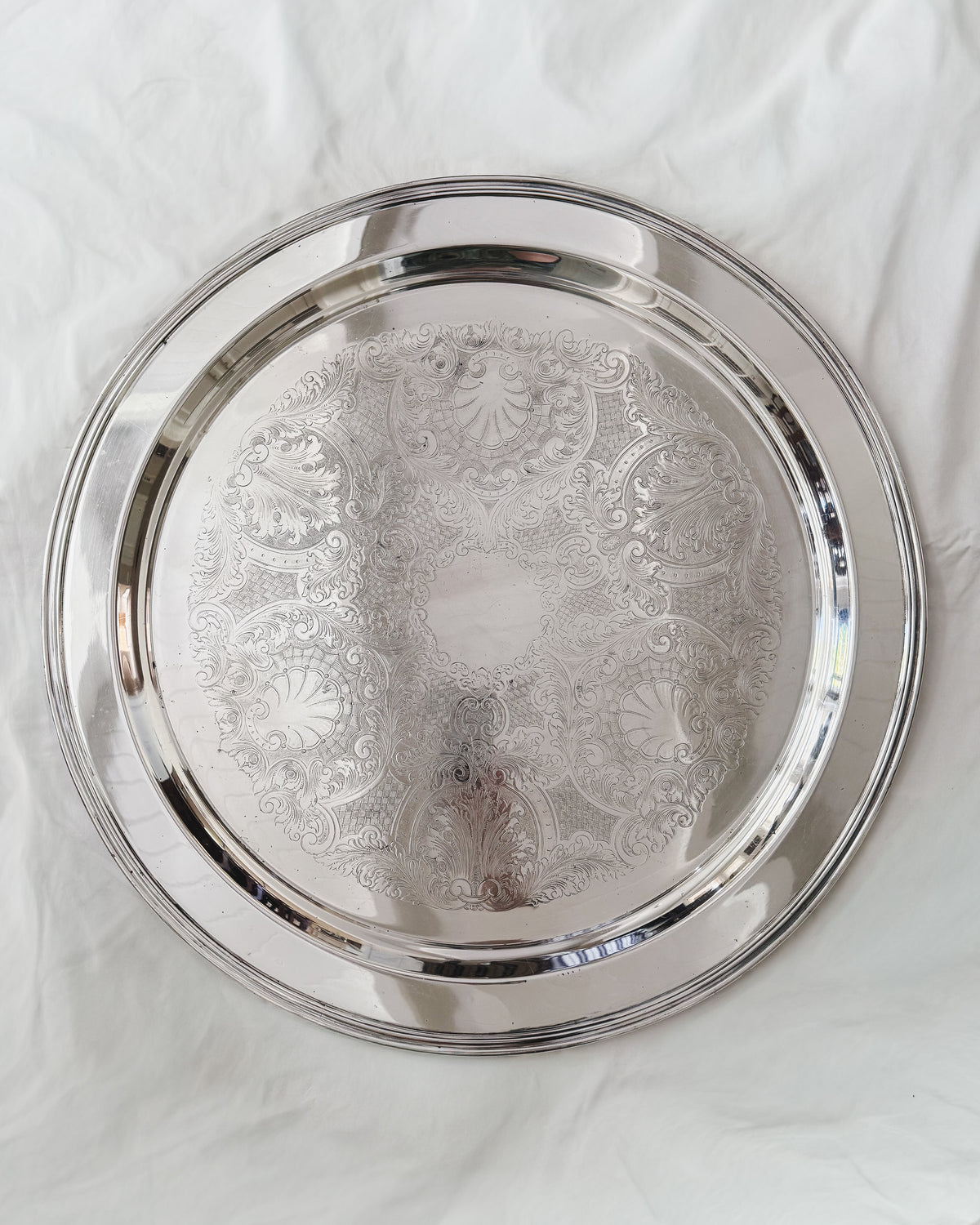 Vintage silver plate oversized round serving tray with engraved shell and foliate decoration, 21 inches