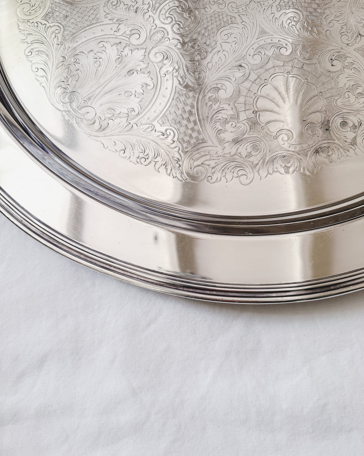 Detail of oversized vintage silver plate tray with engraved shell and foliate motifs